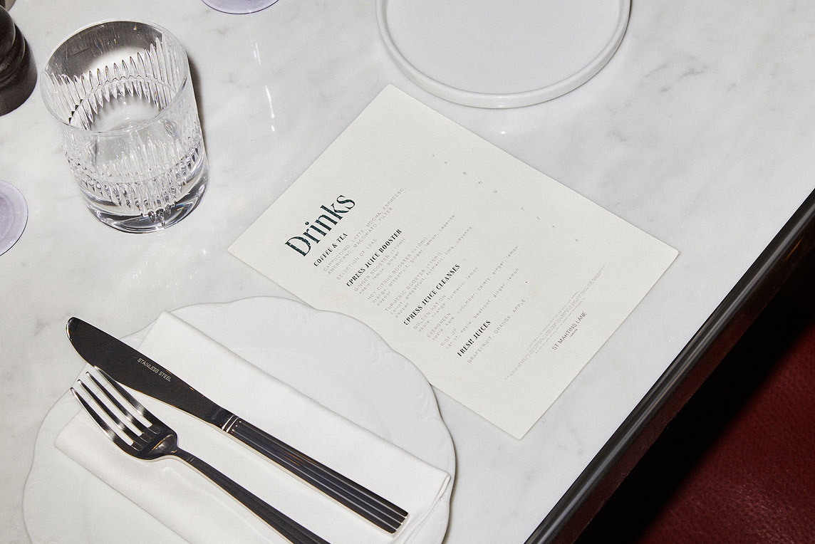 Drinks menu for St Martins Lane on a white marble table with cutlery on the side.