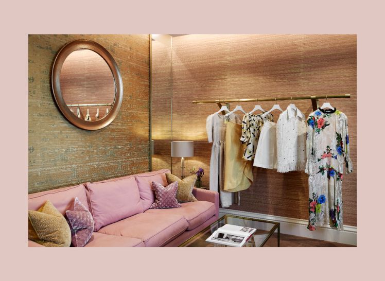Boutique with pink sofa, circular mirror, and clothing rack with clothes