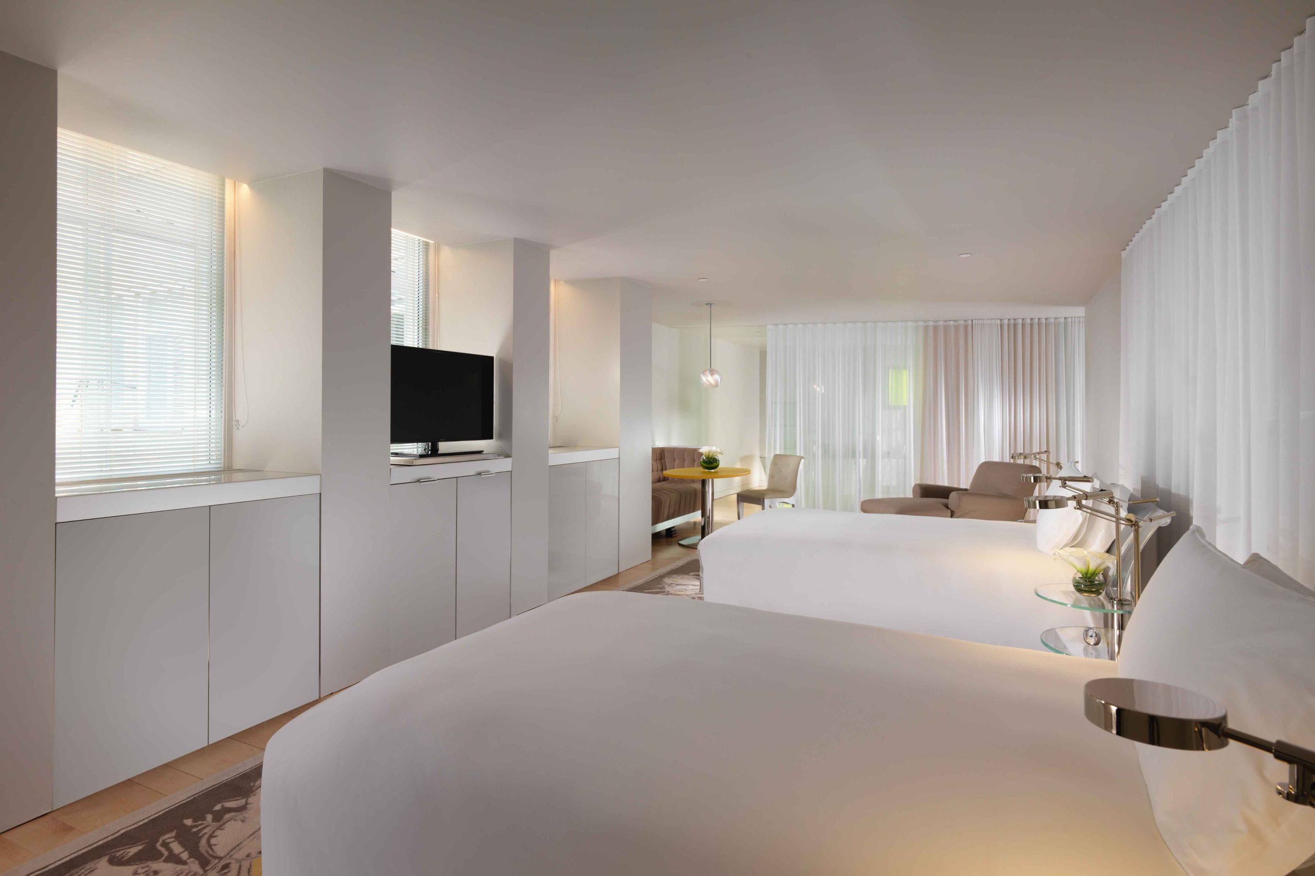 Two white double beds facing a tv on opposite wall in a room at Sanderson London