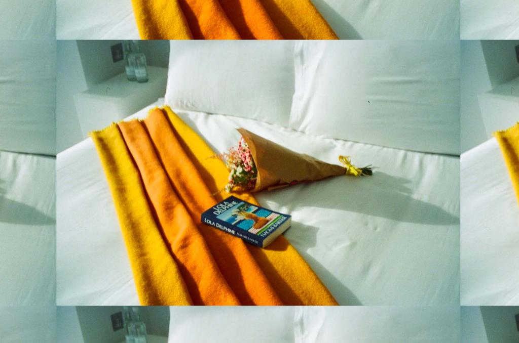 Repeating image of white bed with orange throw blanket, book, and bouquet of flowers