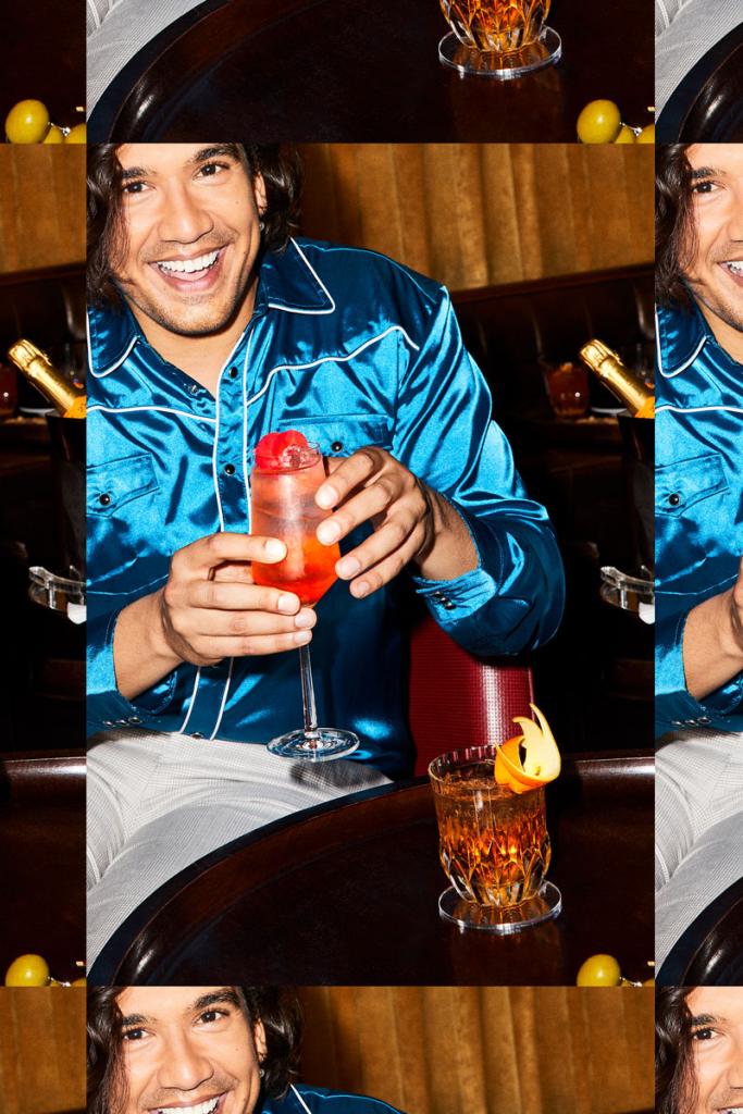 Repeating image of man in a silk blue shirt in a lounge holding a cocktail and smiling
