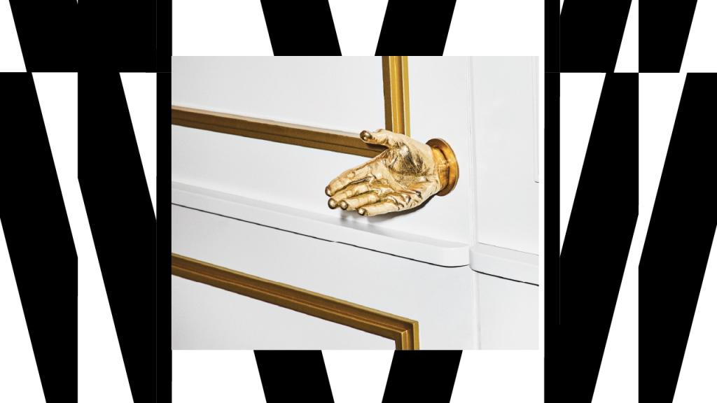 White door with golden hand as doorknob and black and white stripes as background
