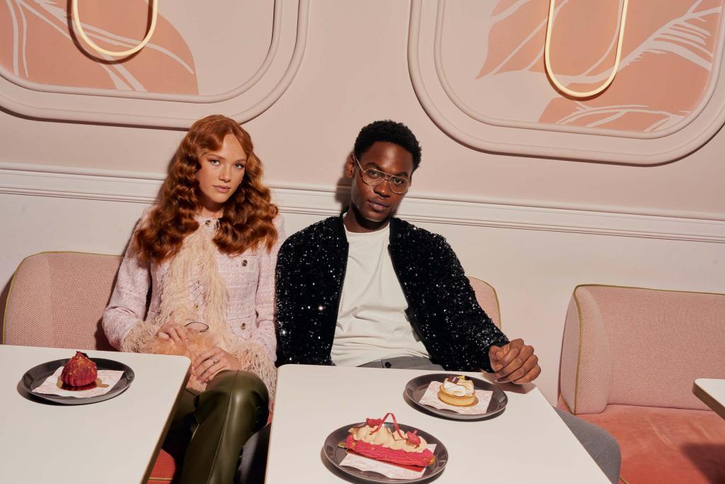 Man and woman sit in pink dinner area with desserts on a white table