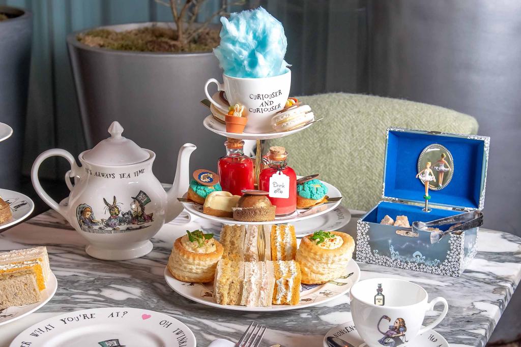 Marble table with mad hatter tea set and cake stand with pastry and finger sandwiches