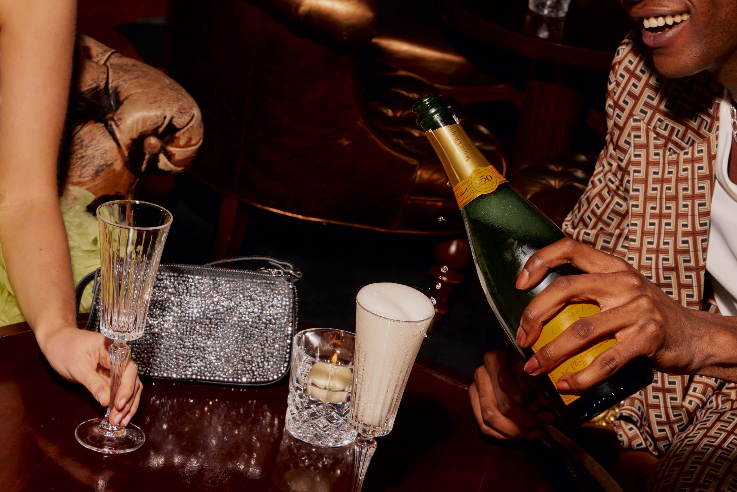 Man pouring champagne into a glass for him and for a female guest.