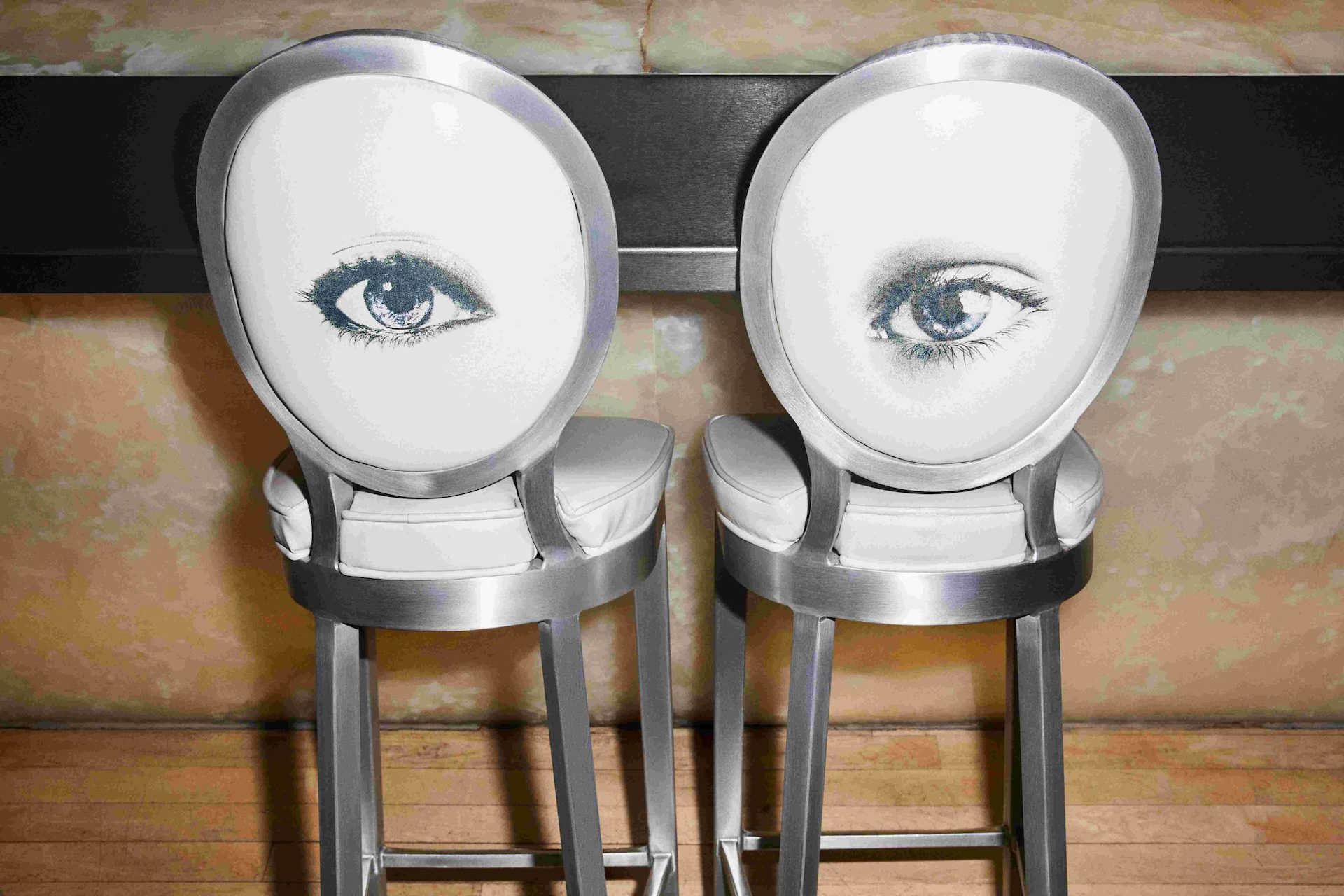 Two white bar stools with eyes printed on the back of both