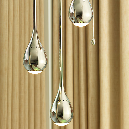 Three gold tear drop hanging lights with beige curtains in the background