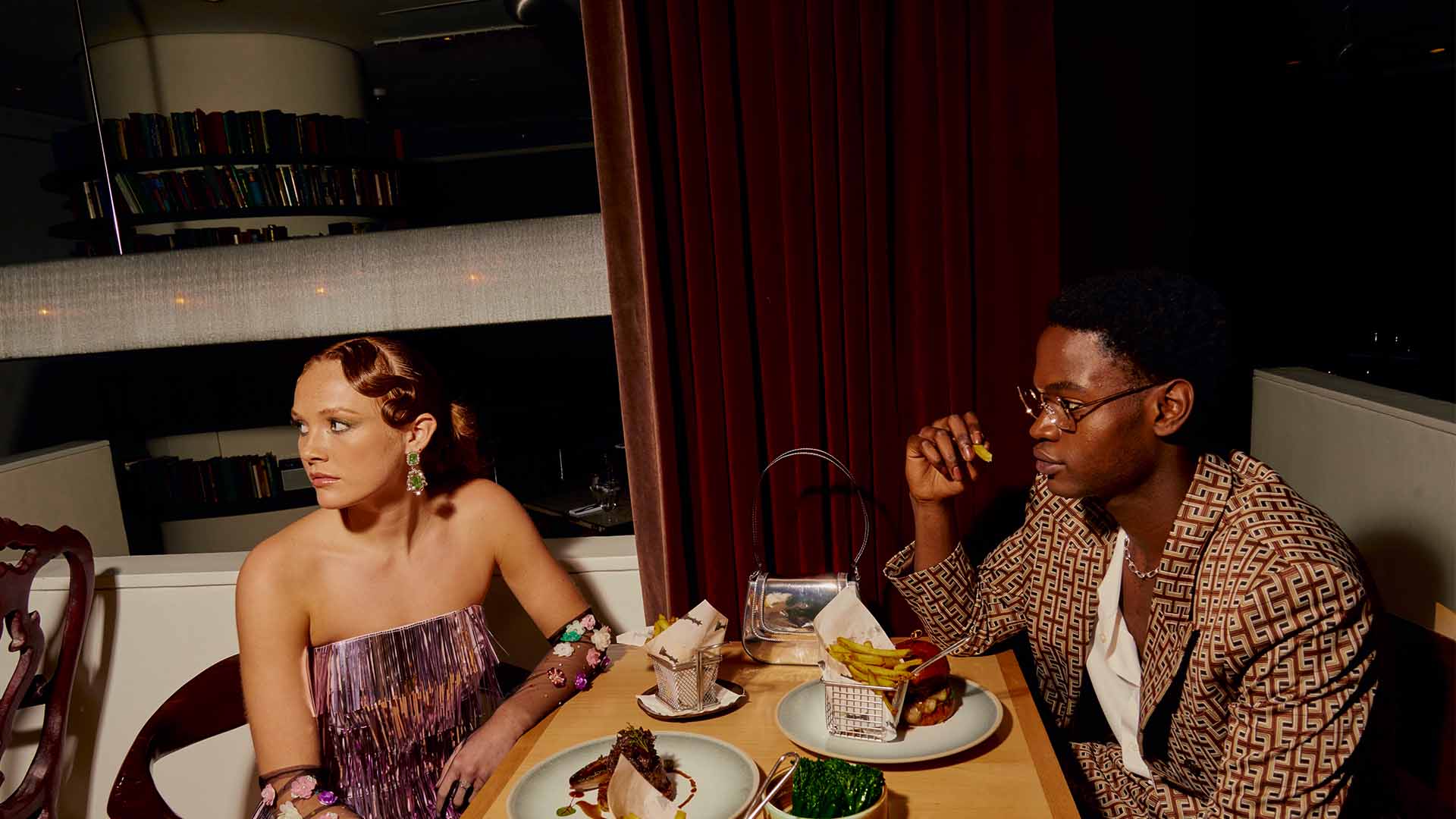 Man and woman in dressy clothes sitting at table with multiple dishes