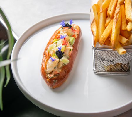 Lobster roll and french fries on a white plate