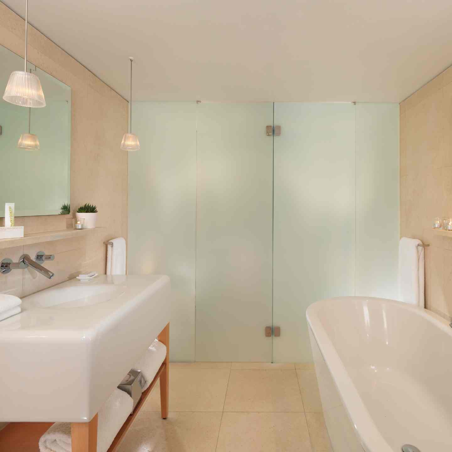 Bathroom with cream walls, white free-standing tub, walk-in shower with glass doors, and large white sink