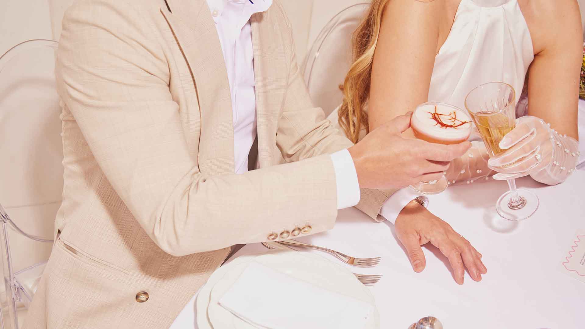 Bras d'un homme tenant un cocktail et applaudissant avec une main de femme tenant du champagne