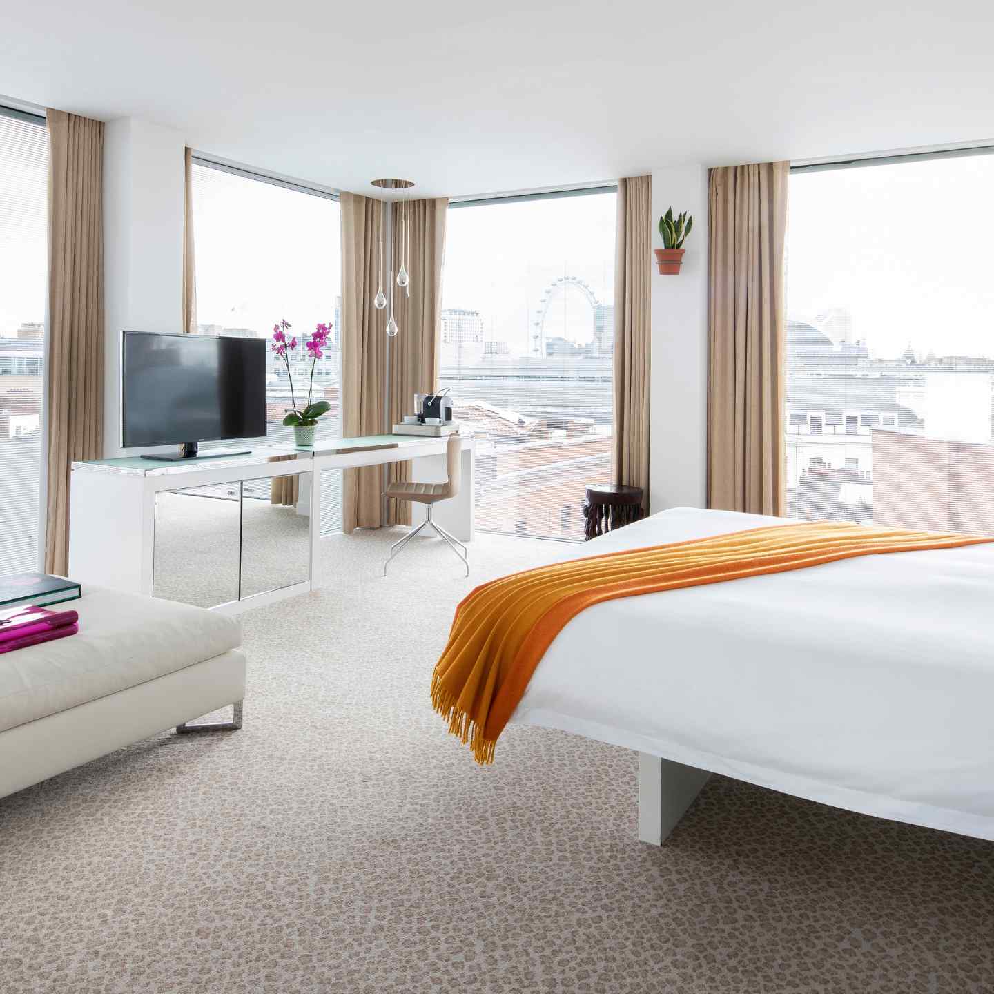 A hotel room full of natural light from floor to ceiling windows