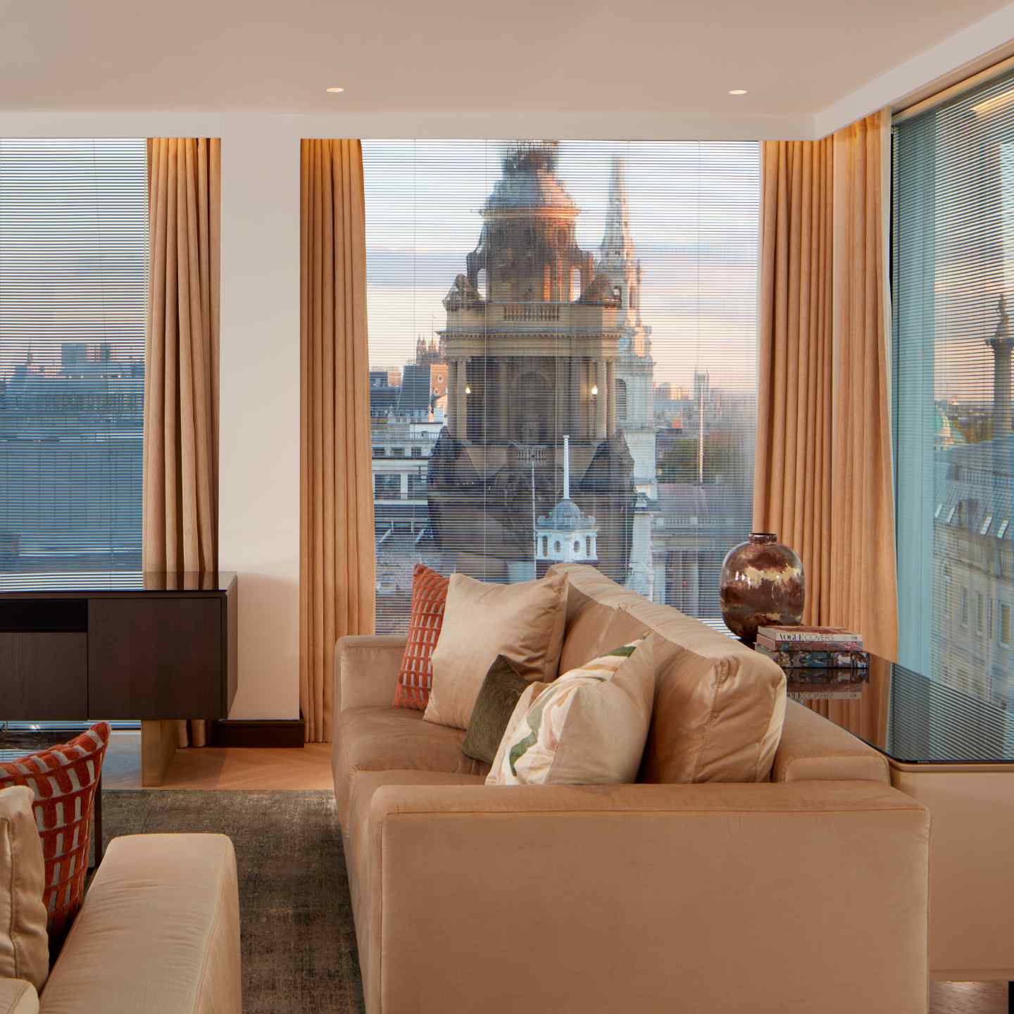 Views of London buildings out of the floor to ceiling windows, with a sofa in the foreground