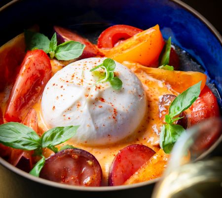Close-up of burrata with tomatoes, basil, and cream sauce