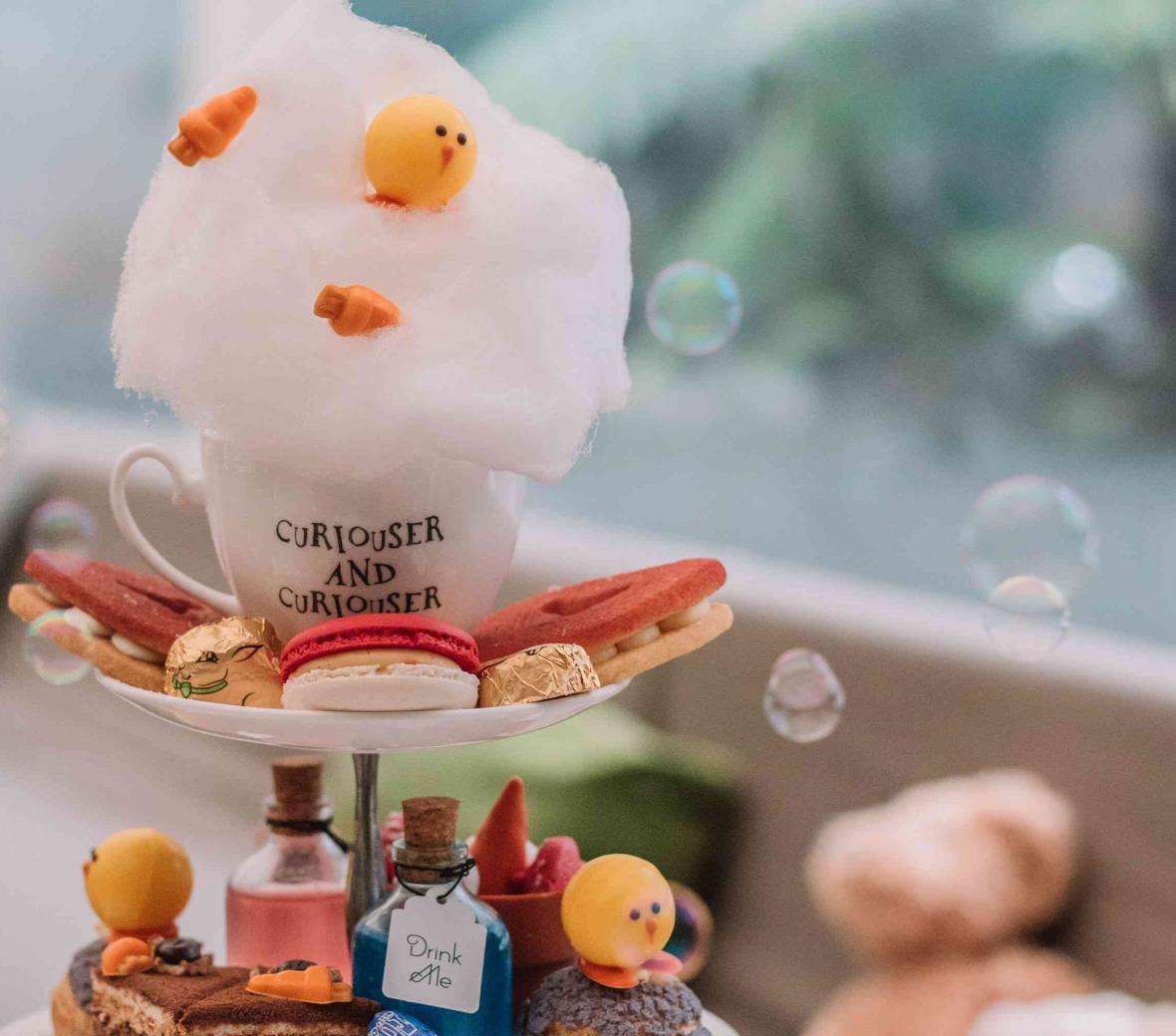 Tea tower with duck themed pastries and tea cup that says Curiouser and Curiouser