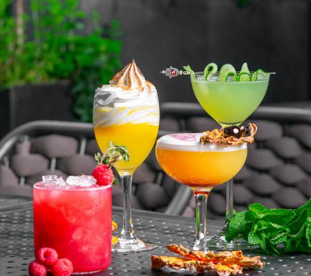 Four colorful cocktails sitting on an outdoor terrace