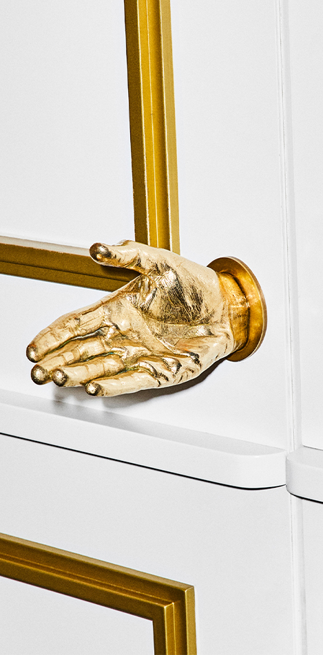 White door with gold outlines and a golden hand as the doorknob